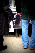 John Lennon's face peeks out from behind two pairs of legs at a vendor's booth near the memorial.